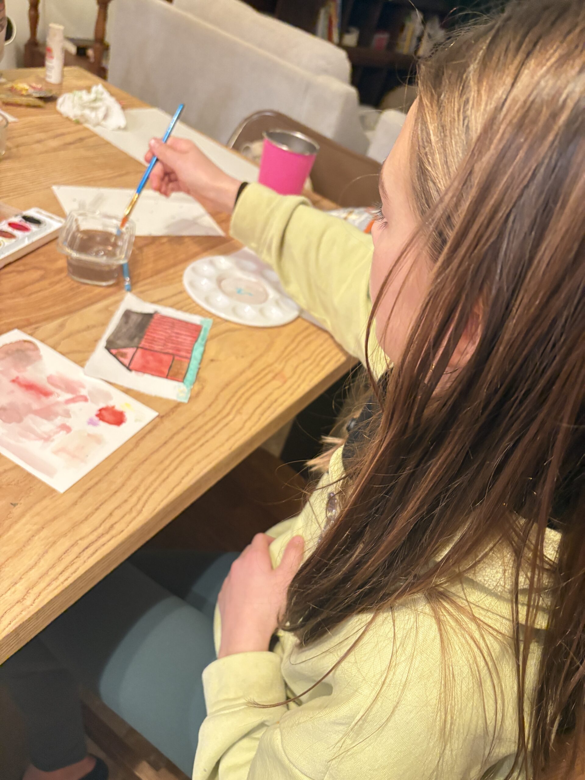 a girl working on a painting project at a table